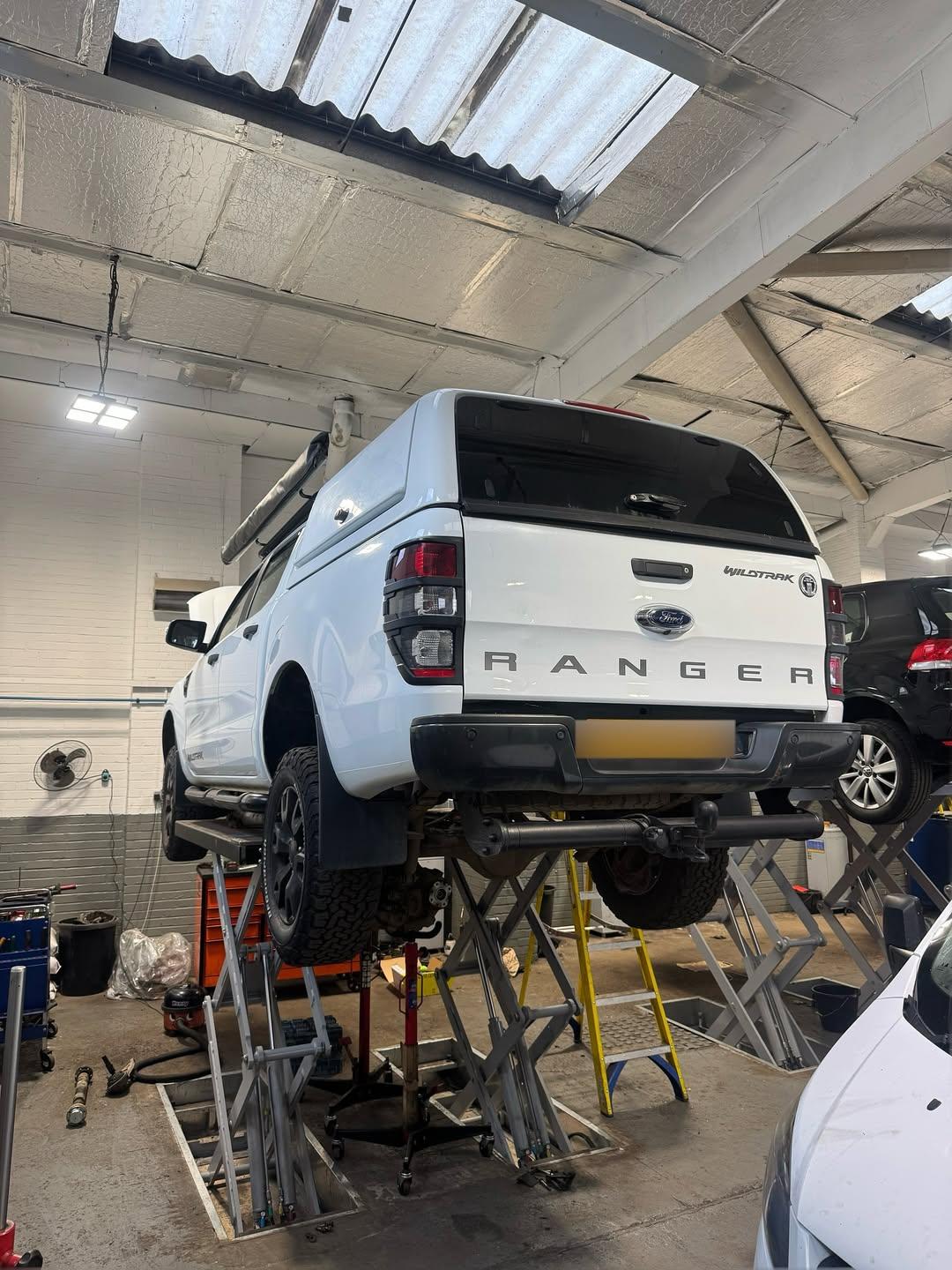 White Ford Ranger pickup raised on a garage lift