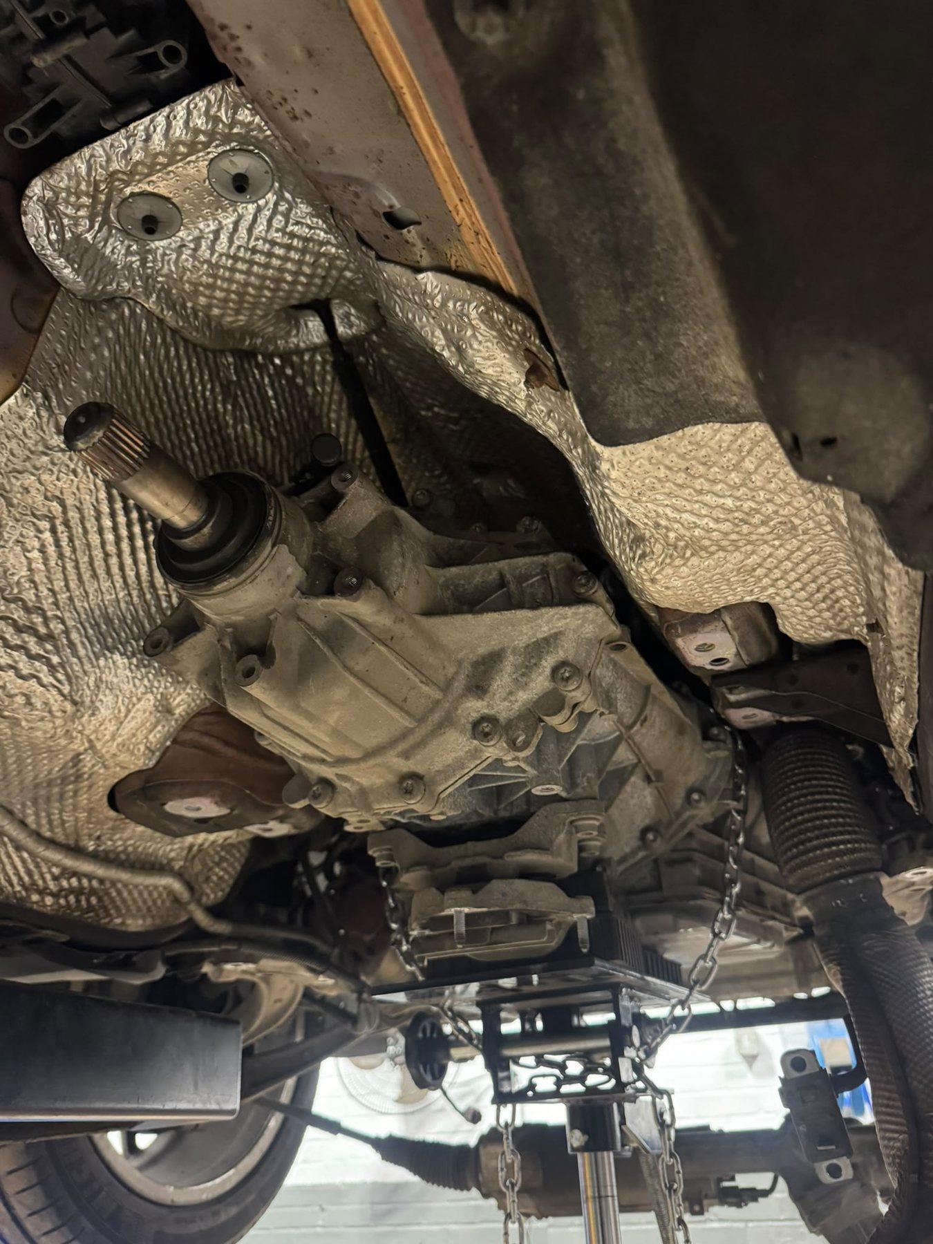 Close view beneath a vehicle showing the installed gearbox and surrounding components