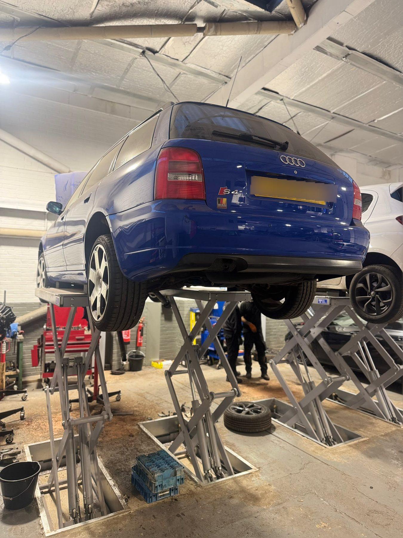 Blue saloon car raised on a garage lift