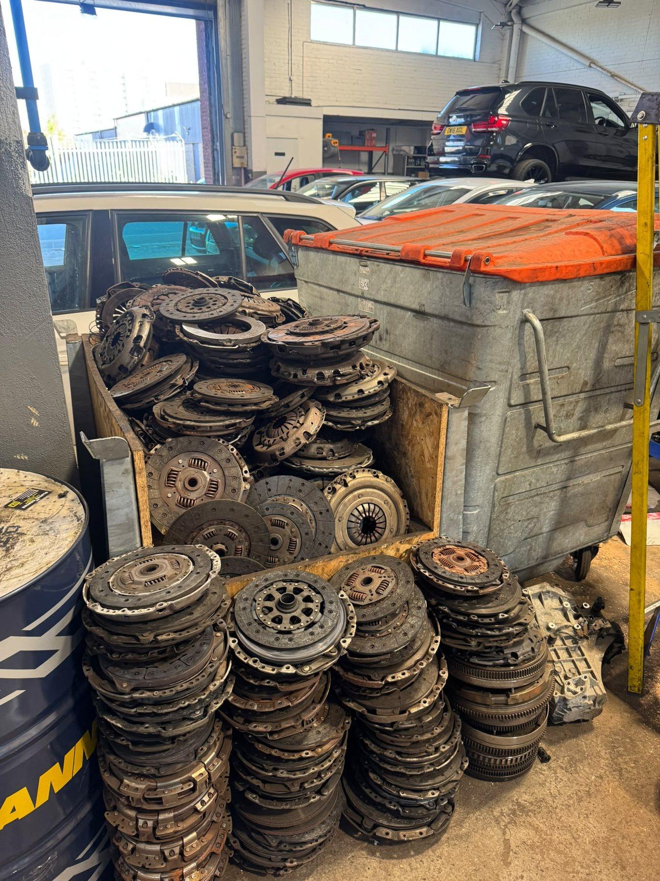 Stacks of removed clutch discs, pressure plates and flywheel components in the garage